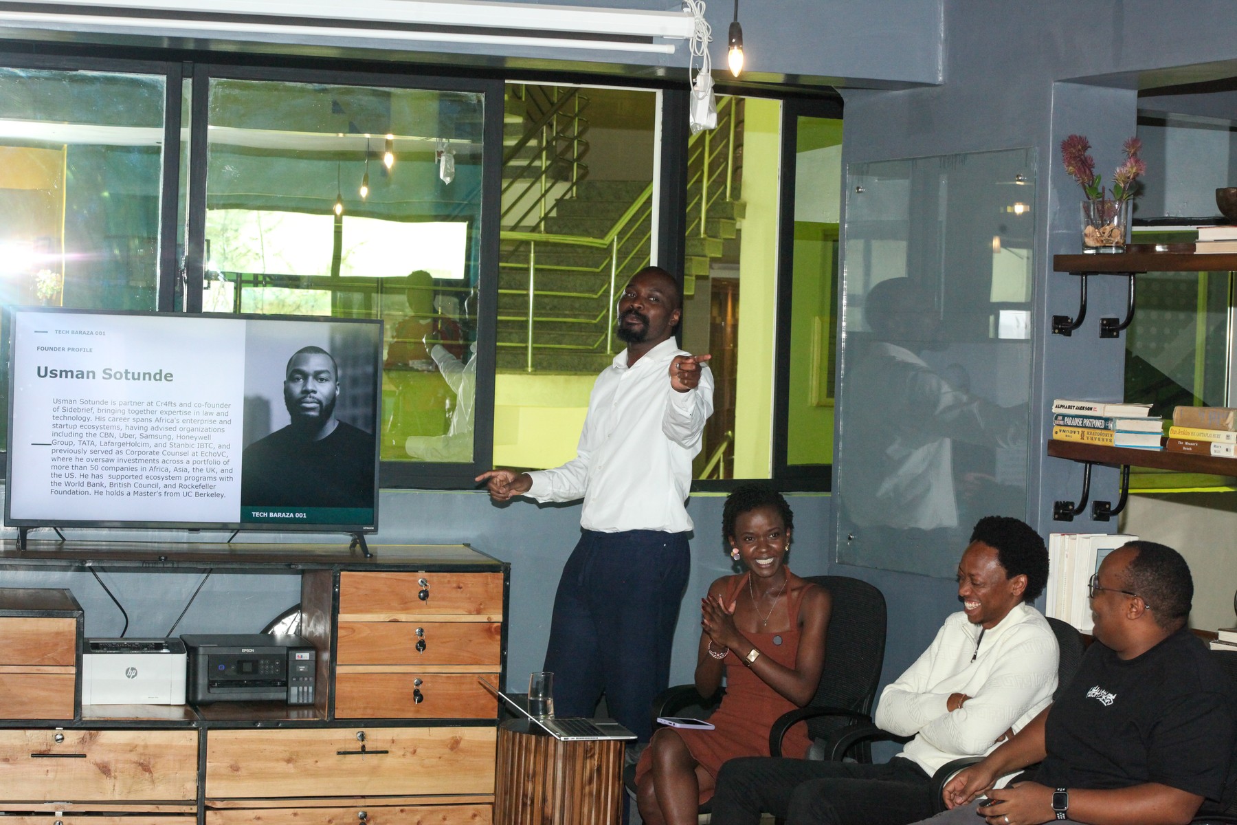 A man presenting beside a screen to a seated group