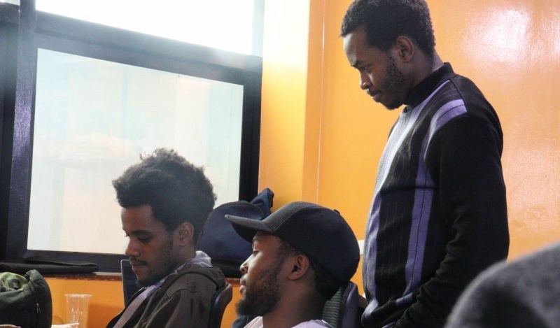 A mentor reviewing work beside two seated builders