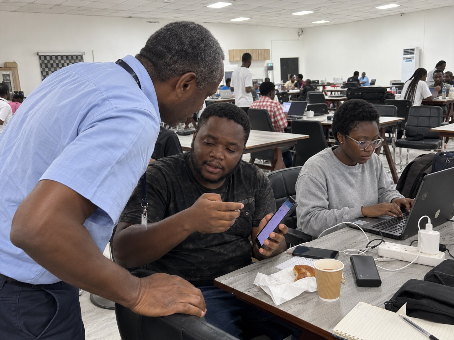 A mentor looking at a builder’s working app on his phone