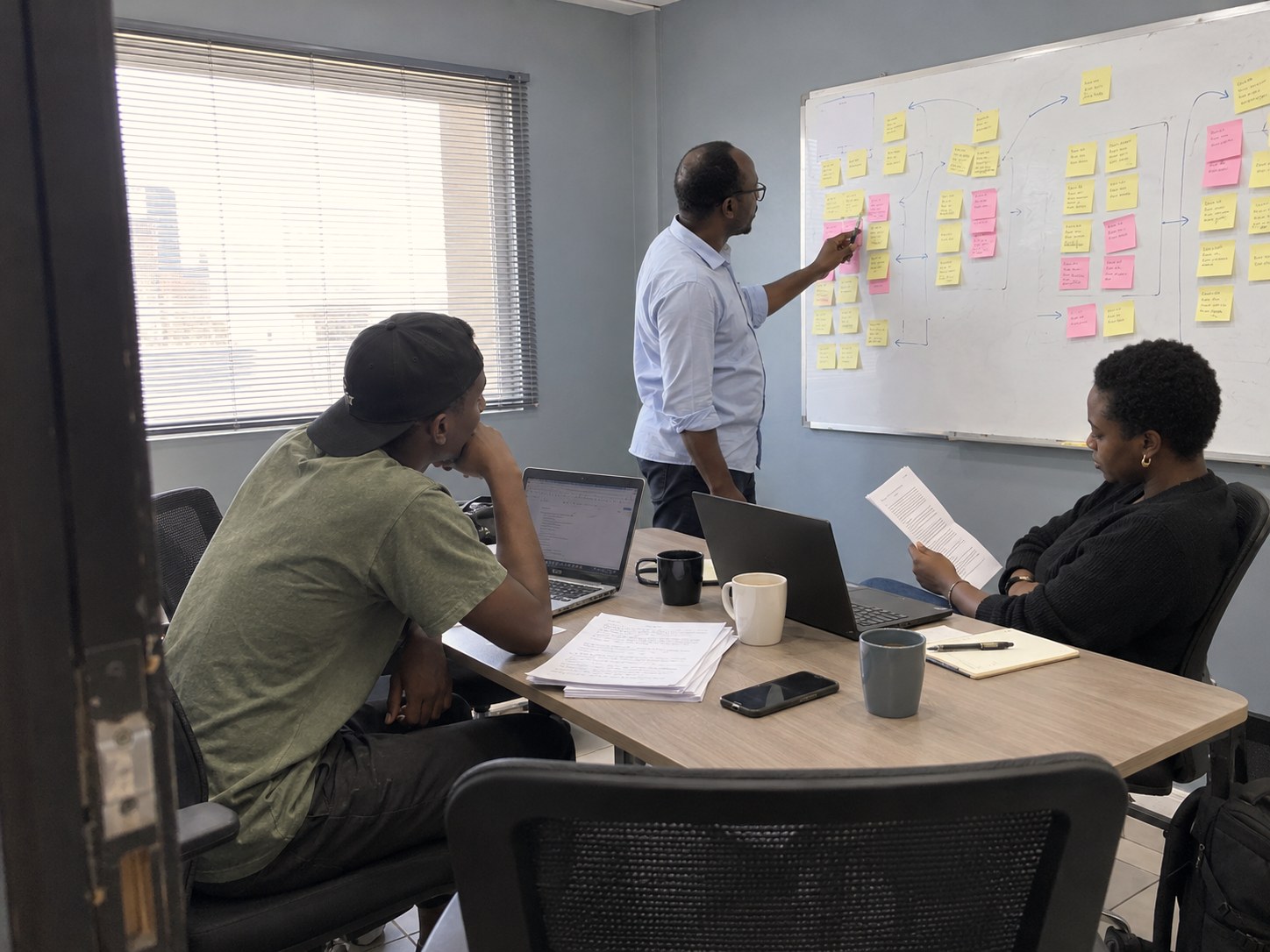A founder and two partners reviewing interview notes at a whiteboard