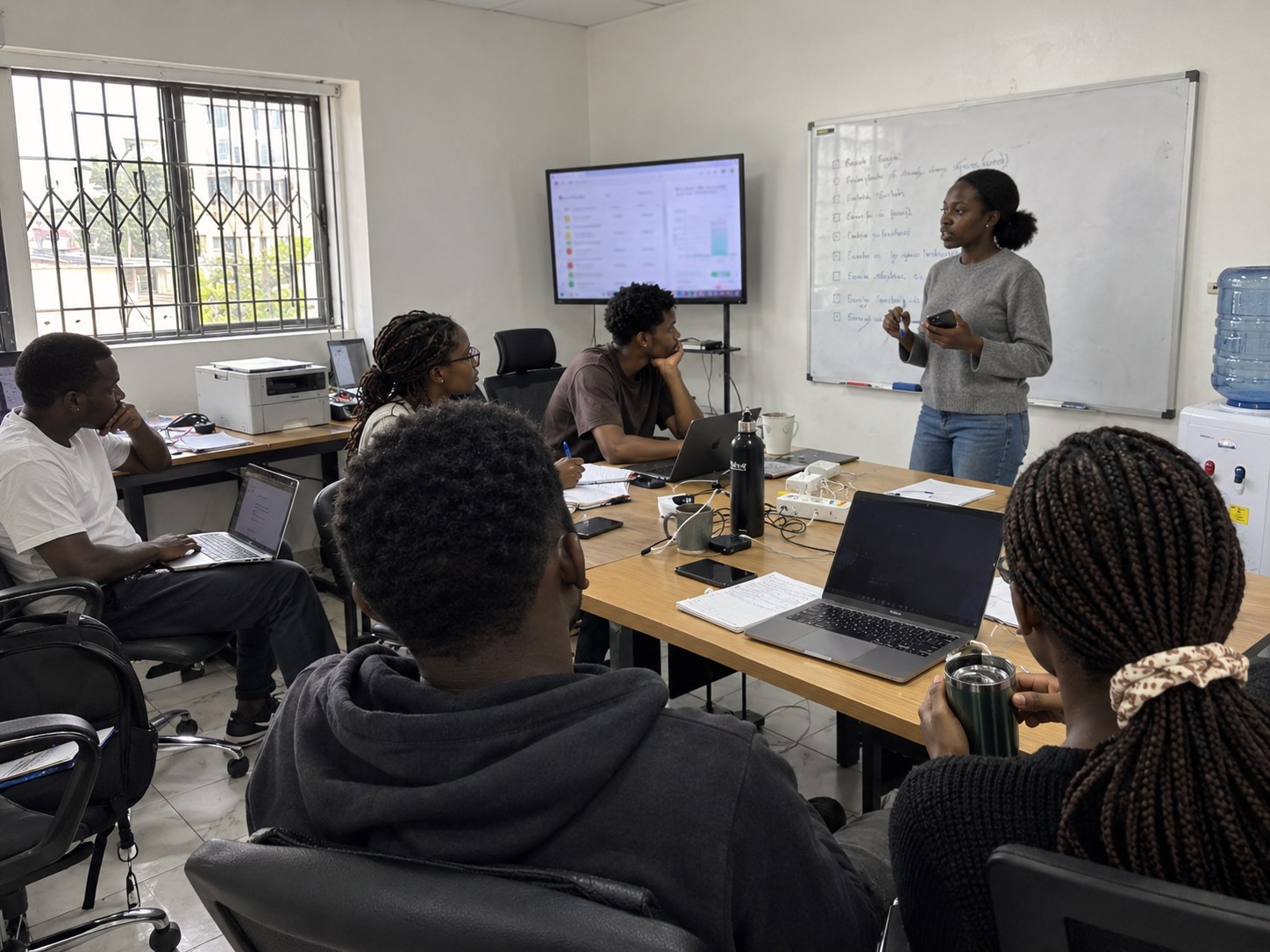 A founder running a team meeting at a whiteboard